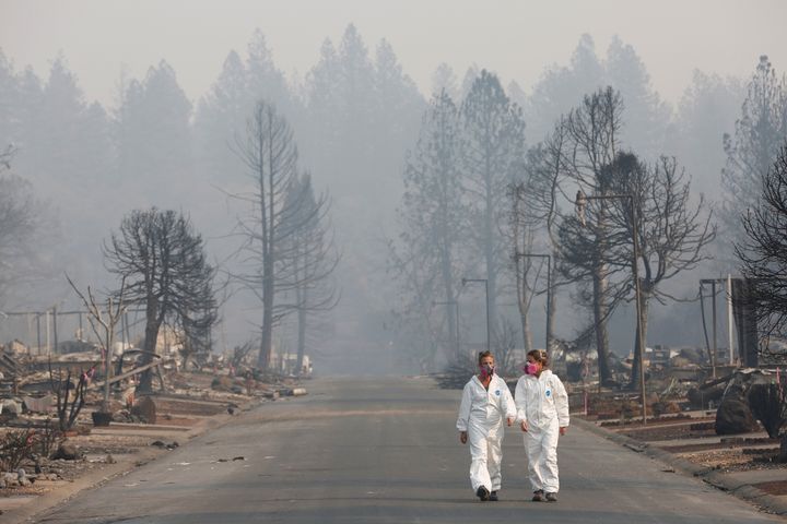 Forensic anthropologists Kyra Stull (L) and Tatiana Vlemincq walk through a trailer park destroyed by the Camp Fire in Paradi