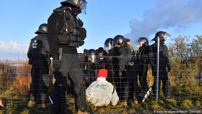 Police offers stand around a climate protester at the United Schleehain mine in eastern Germany (picture-alliance/dpa/H. Schmidt)